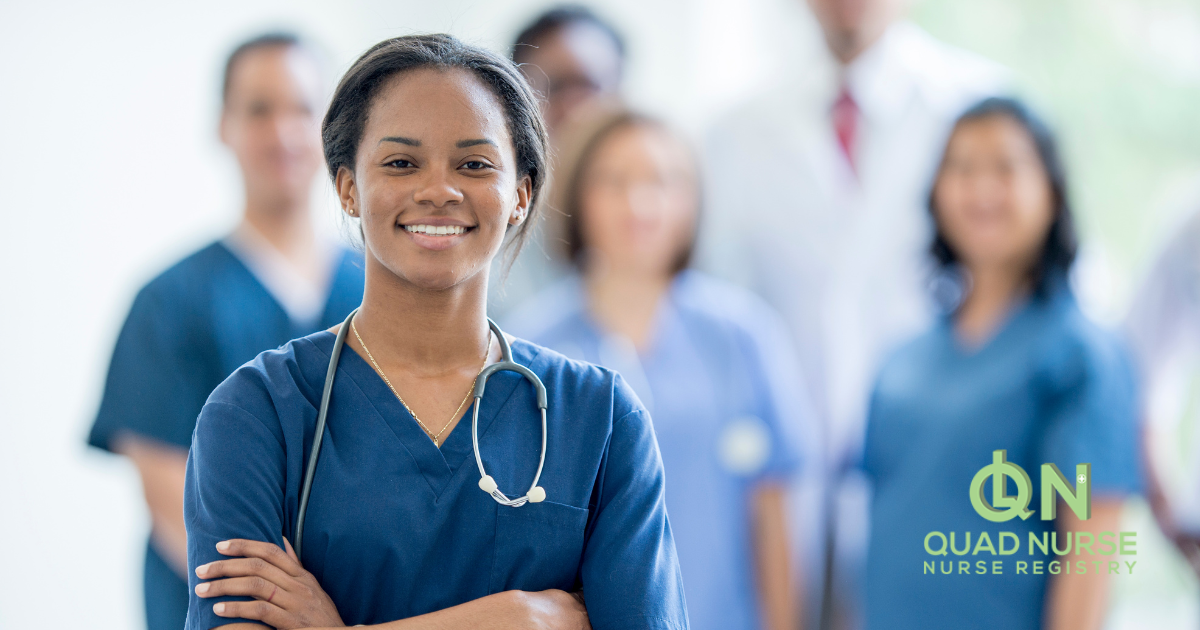 A smiling nurse stand with other nurses and professionals in the background.